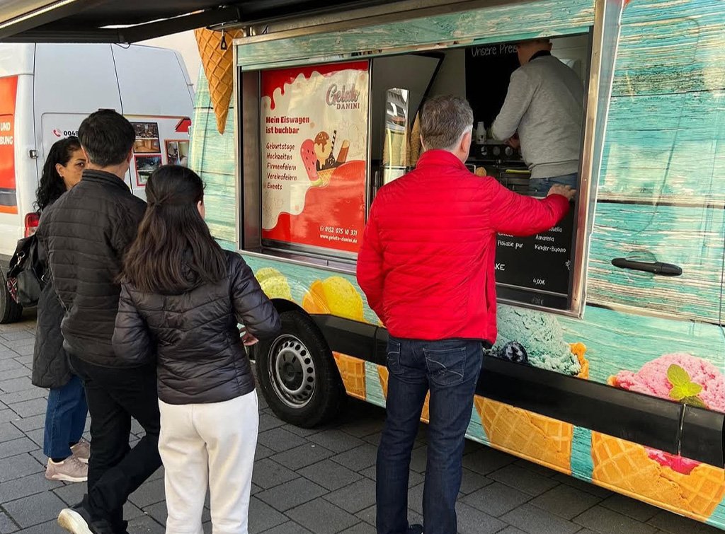 Menschen stehen vor dem Danini Foodtruck und bestellen warme Getränke und Süßes an einer Straßenaktion.